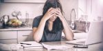 woman in kitchen feeling stress over bills